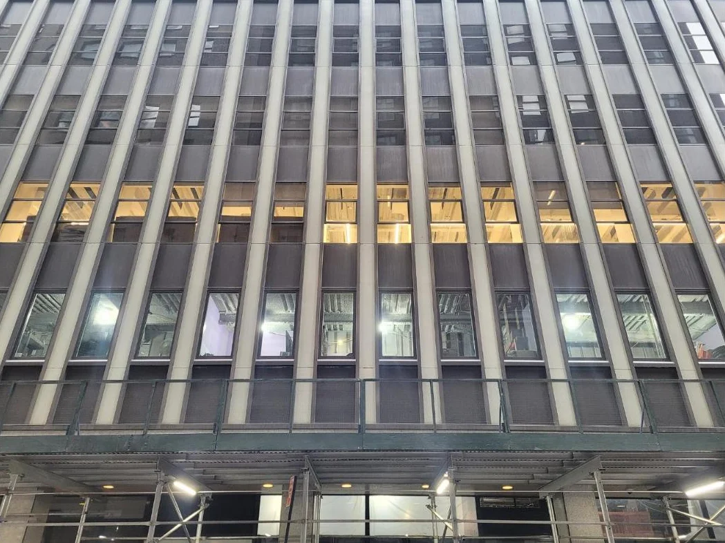 Close view of a mid-century office facade with vertical stone fins and lit windows