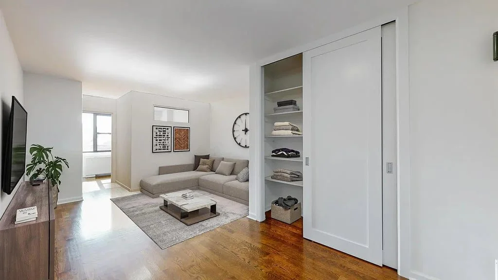 A long, bright living room with hardwood floors, a sofa and a sliding partition door