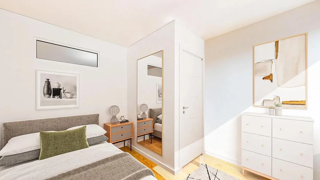 A bedroom with a pale wood bed, a green pillow and a white dresser