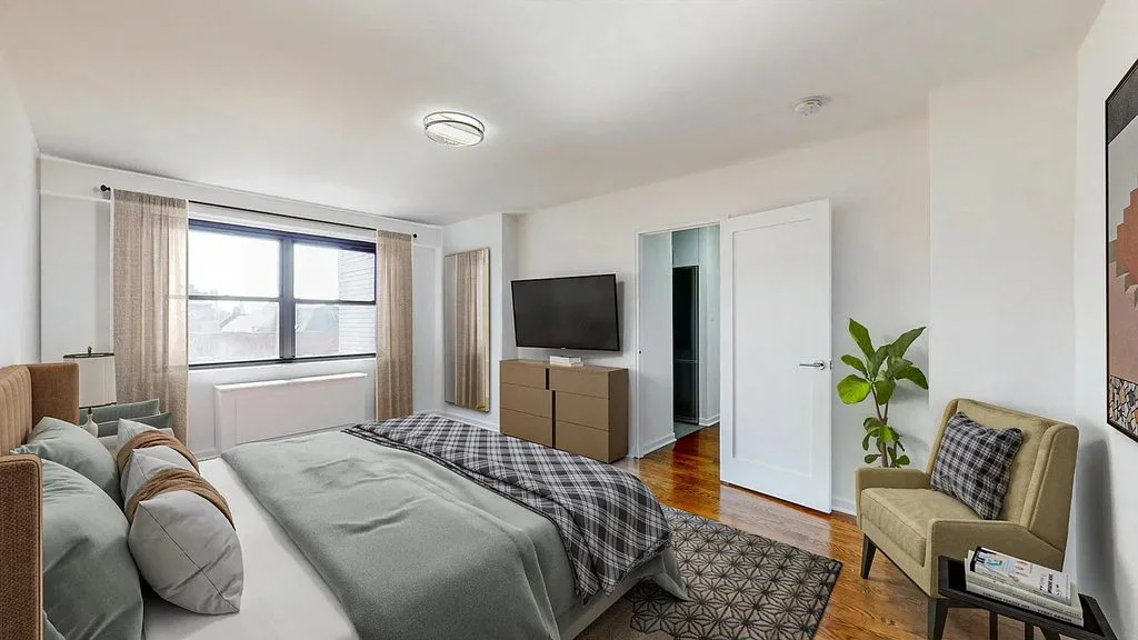 A bedroom with a window, a grey armchair and a patterned rug