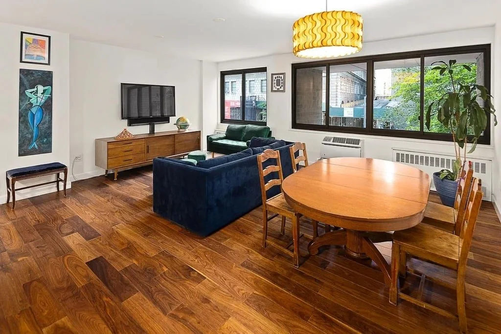 The open living and dining room with hardwood floors and a round dining table under a gold pendant light
